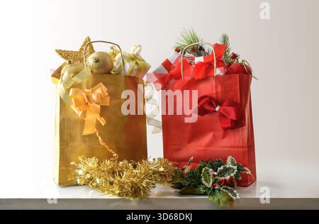 Red and gold paper gift bags with Christmas decorations inside and isolated white background. Front view. Stock Photo