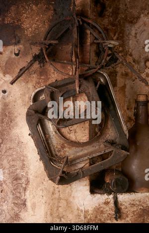 close-up of rusty cooker parts hanging on dirty wall, old iron burner grate and drip tray covered in grime, vintage metal shop background with decay Stock Photo