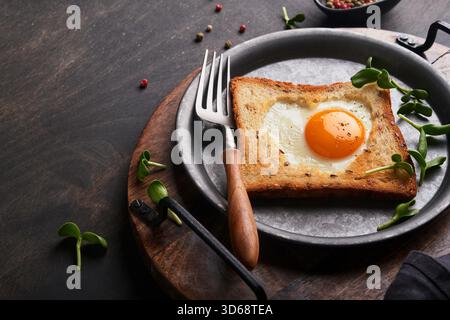Valentines day breakfast. Fried eggs and bread in the shape of a heart and fresh vegetables on old wooden rustic background. Breakfast with surprise for loved ones. Mock up. Stock Photo
