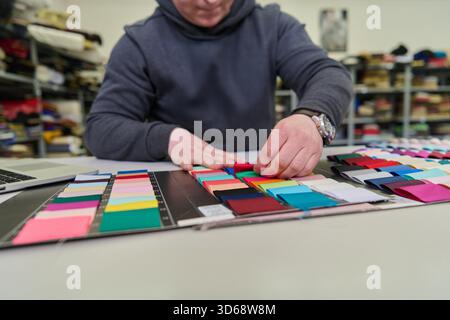 Fashion designer selecting fabric swatches and textile samples. This image can be used for fashion design, textile industry, or creative process concepts. It shows the material choice for clothing design. || Model released Stock Photo