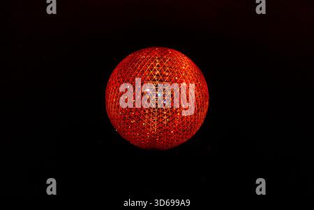 A radiant red sphere composed of triangular lattice patterns glows vividly against a black background, showcasing intricate geometric symmetry Stock Photo