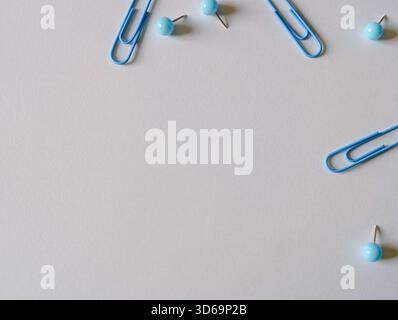 Minimalist flat lay of blue office supplies (paper clips and pushpins) on a white background with ample copy space Stock Photo