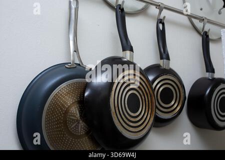 A view of several pots and pans hanging on a wall rack. Stock Photo