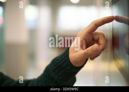 Caucasian young adult man hand interacting with touchscreen device in modern business environment, finger pressing digital interface, technology usage in professional setting Stock Photo