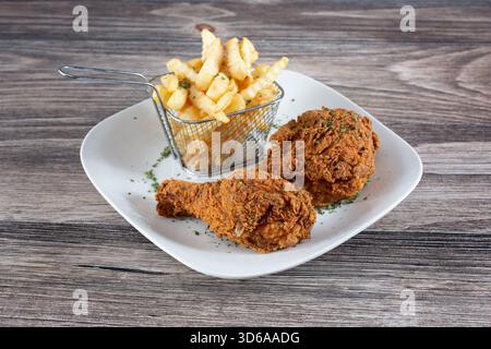 A view of a plate of fried chicken drumsticks and french fries. Stock Photo