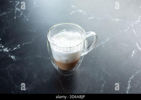 A view of a flat white coffee drink inside a clear plastic mug. Stock Photo