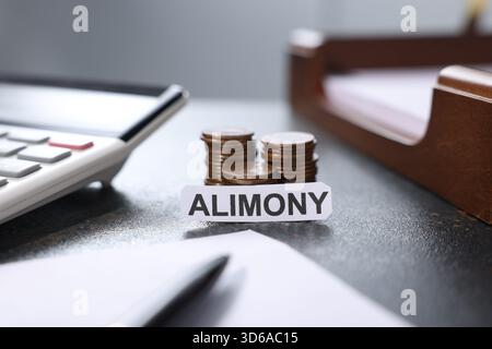 Paper note with word Alimony, coins, calculator, documents and pen on dark table, closeup Stock Photo