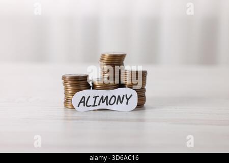 Paper note with word Alimony and coins on wooden table, closeup Stock Photo
