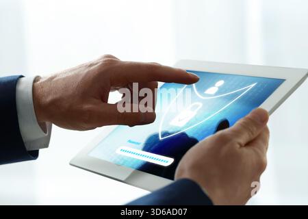 Man unlocking tablet computer, closeup. Password box and shield illustration on device screen. Cyber security and data protection concept Stock Photo