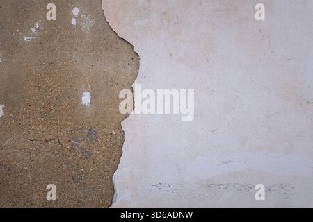 Textured wall with a mix of rough brown and smooth white surfaces. The brown area shows signs of wear and age, while the white section appears clean Stock Photo
