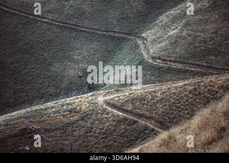Telephoto winter view of winding hillside paths cutting through textured grass and scrub in Asturias, forming organic geometric lines and a rugged, re Stock Photo