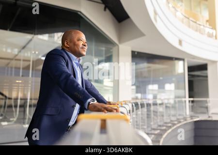 Mature African American businessman standing indoors and looking ahead with thoughtful smile Stock Photo