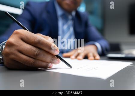 Closeup of mature African American businessman signing document in the office Stock Photo