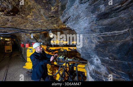 PRODUCTION - 14 November 2025, Saxony, Annaberg-Buchholz: Gunnar Lenhard stands at a drill rig underground in the Markus Röhling Stolln mine in Annaberg-Buchholz. In today's visitor mine, an old mining custom is kept alive, the Mettenschicht. The Mettenschichten has existed for around 400 years and is the miners' last shift before Christmas. When the visitor mine was established, the idea was born to revive this custom. Up to 80 people are entertained down here by candlelight on several dates during the Advent season, with bacon fat sandwiches and lentil soup, accompanied by music. The traditi Stock Photo