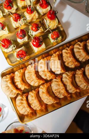 Overhead view of assorted canapes and dumplings on gold trays at luxury catering event. Stock Photo