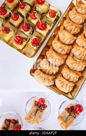 Overhead view of assorted canapes and dumplings on gold trays at luxury catering event. Stock Photo