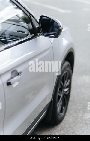 Modern white SUV side view with sleek mirror and handle, parked on asphalt. Stock Photo