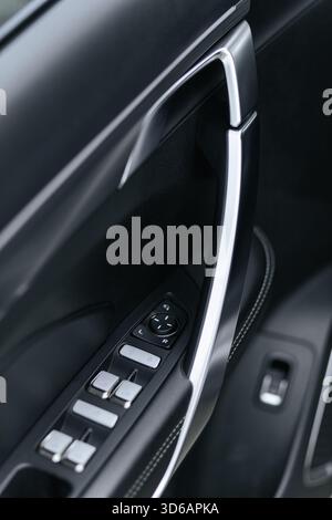 ?loseup of a car's driver door controls for windows and mirrors, featuring chrome accents on black leather Stock Photo