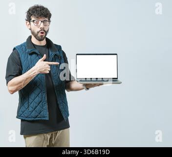 Portrait of bearded handsome man showing laptop screen isolated. Surprised Handsome Man with glasses displaying a promotion on computer screen Stock Photo