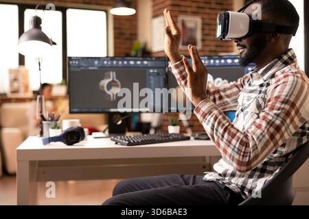 Focused black designer using virtual reality headset to develop digital building models for construction projects. Advanced immersive technology supporting interactive design review. Stock Photo