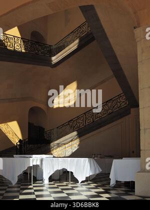 The lobby of a southern hotel. Tables covered with crisp white tablecloths stand on a checkerboard-tiled floor. Sandstone cladding. Casablanka Stock Photo