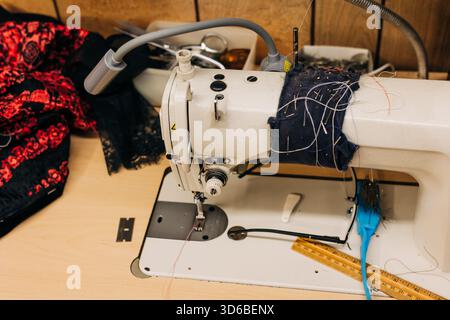 Sewing machine with colorful fabric and tools on a work table in a crafting space during the day Stock Photo