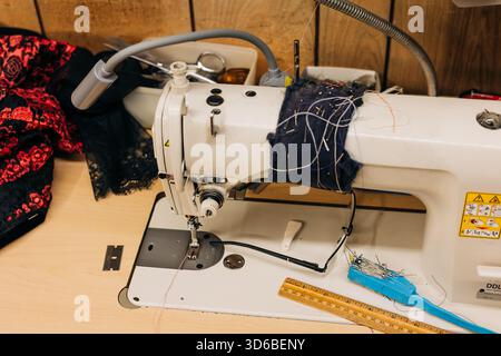 Sewing machine with colorful threads and sewing tools in a crafting space during daylight hours Stock Photo