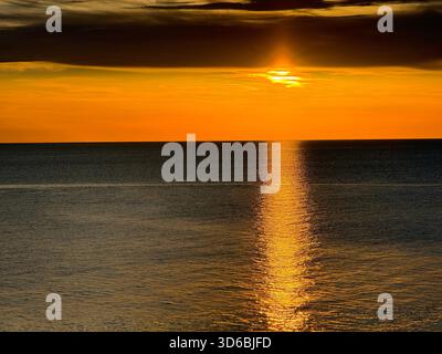 Sunset bright orange sky over calm sea dark water Stock Photo