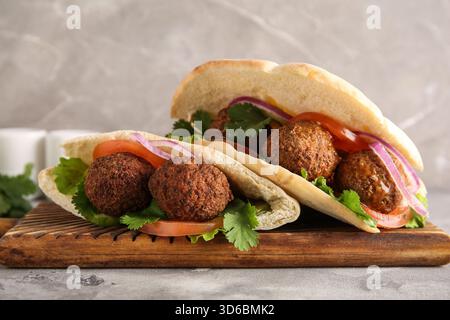 Wooden board of delicious pitas with falafel on grey background Stock Photo