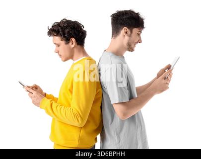 Young brothers using mobile phone and tablet computer on white background Stock Photo
