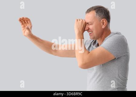 Mature man looking through imaginary telescope on light background Stock Photo