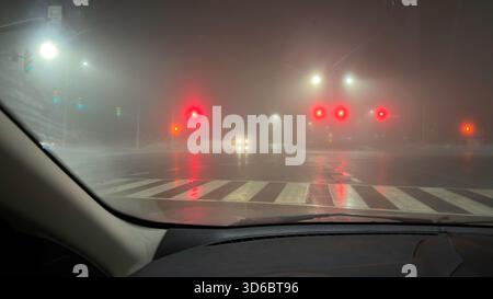 Road intersection at rainy night as seen from a car driver's point of view Stock Photo