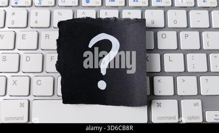 Digital Question and Online Help Concept with Question Mark on Black Paper Centered on Modern Computer Keyboard Stock Photo