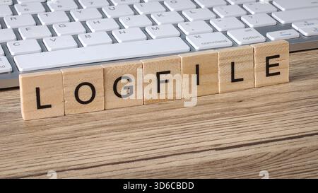 LOGFILE Word Spelled Out on Wooden Blocks Placed on Keyboard Representing IT Debugging and System Records Stock Photo