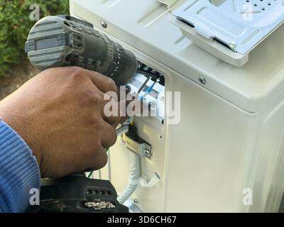 worker connects electric wires to installation of the air conditioner Stock Photo