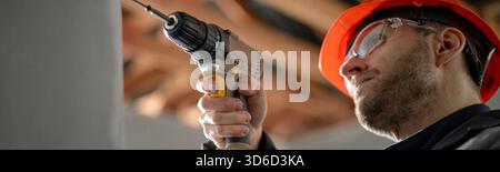 Caucasian Young Adult Man Using Electric Drill While Working Indoors Stock Photo