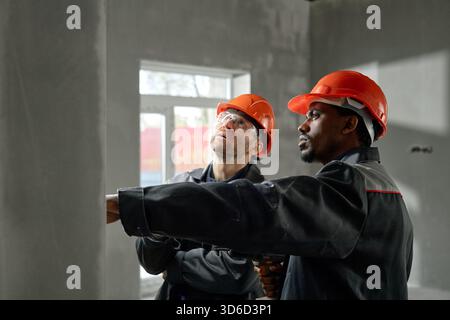 Middle Aged Caucasian Man and Black Man Inspecting Construction Site Indoors Stock Photo