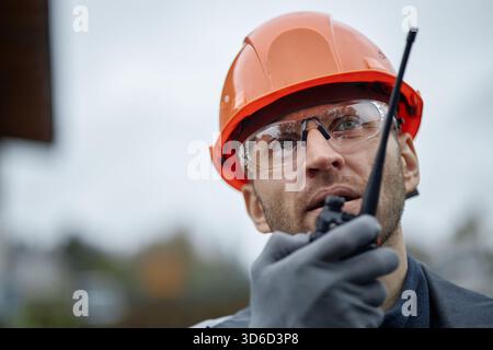 Caucasian Middle Aged Man Wearing Hard Hat Using Walkie Talkie Outdoors Stock Photo