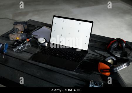 Laptop Displaying Calibration Screen Surrounded by Construction Tools on Table Stock Photo