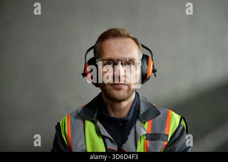 Portrait of Caucasian Young Adult Man Wearing Safety Gear Working Indoors Stock Photo