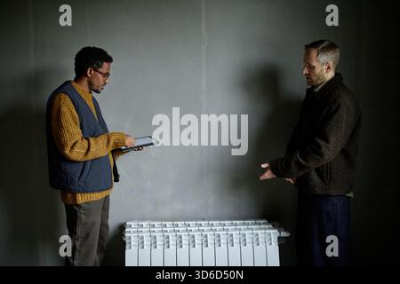 Middle Aged Black Man Using Digital Tablet While Caucasian Man Explaining Stock Photo