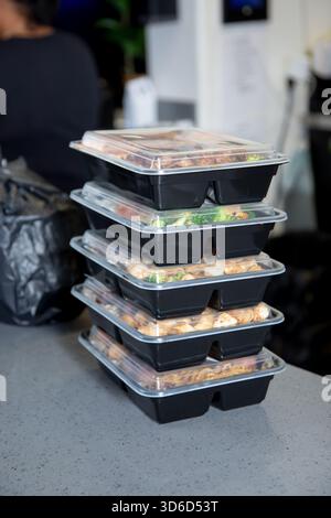 A view of a stack of food orders packed inside plastic to-go containers on the counter. Stock Photo