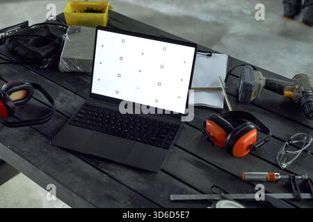 Laptop Displaying Calibration Screen on Workshop Table Surrounded by Tools Stock Photo