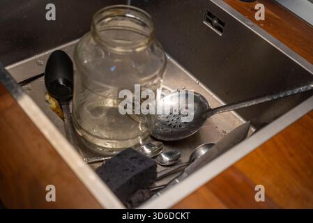 indoor shot of a jar and silverware inside a kitchen sink Stock Photo