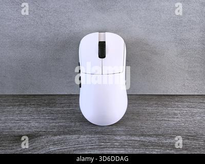 A sleek white gaming mouse poised for action ready to unleash digital prowess on a textured wood Stock Photo