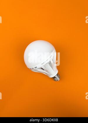Segambut, Kuala Lumpur, Malaysia - Nov 23, 2025 : Flat lay, overhead shot. The light bulb is centered on the vibrant orange background, slightly tilte Stock Photo