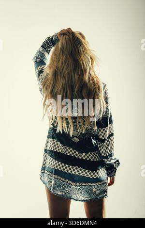Rear view of a blond Caucasian woman standing by the window looking ...