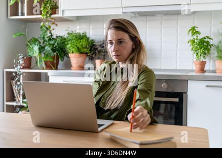 Serious middle aged woman planning family budget, working on laptop, analyzing income and loans. Stock Photo
