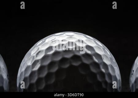Golf ball closeup with rim lighting on dark background Stock Photo