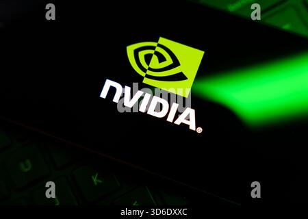 Nvidia logo on smartphone screen over laptop keyboard with green lighting. High quality photo Stock Photo